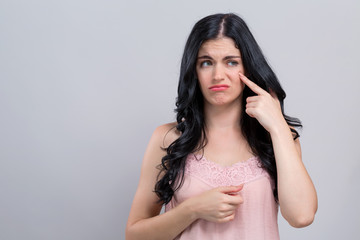 Young woman with skin blemish theme on a gray background