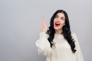 Young woman looking upwards on a gray background