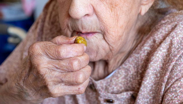 Woman holding olive to eat it peacfully