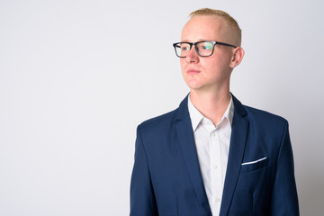 Face of young blonde businessman in suit thinking and looking away