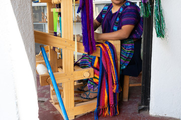 Obraz na płótnie Canvas La tejedora Maya está bordando una pieza de vestir en su tejedora de pie en Guatemala.