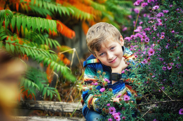 Portrait of a boy on a walk in the autumn Park among bright flowers and trees