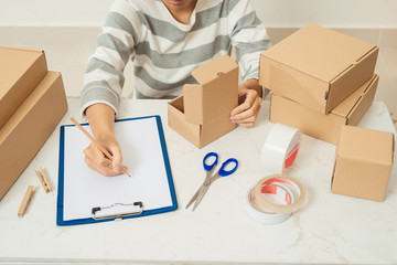 Delivery concept. Woman signs papers among parcels, close up