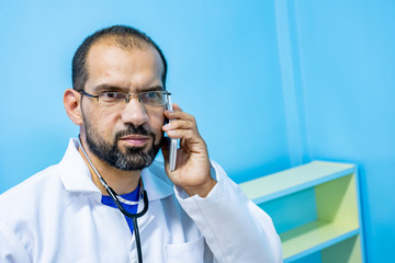 Doctor talking on the phone next to his patient