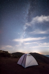 Camping tent under the stars and distant city background