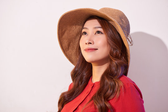 Blissful lady with broad smile posing in sunny day. Laughing girl in red clothes and trendy straw hat enjoying good weather in weekend.