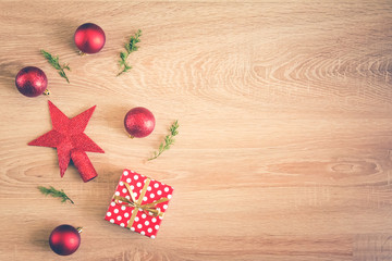 Christmas background - flat lay of red christmas balls, pine cones and a gift box over wooden background. Copy space.