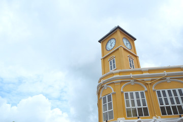 Fototapeta na wymiar The yellow clock tower in old building with cloudy at Phuket city, Thailand.