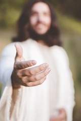 Vertical shot of Jesus Christ reaching out with a blurred background