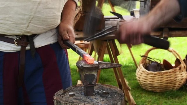 Blacksmiths at work in slow motion with anvil and forge hammering hot glowing metal