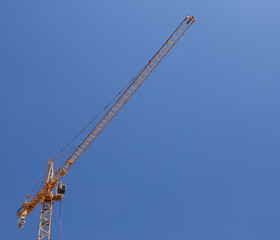 Yellow construction crane against vibrant blue sky