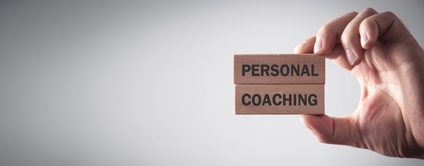 Male hand holding Personal Coaching text on wooden blocks.