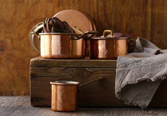 copper utensils, pots, ladle and pan on wooden background