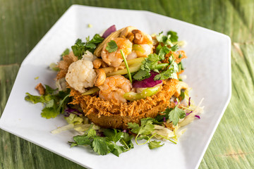 Sauteed shrimp, cashew nuts, cauliflower, corn, and mixed vegetables in a nest made of fried taro. Plated and served on banana leaves.