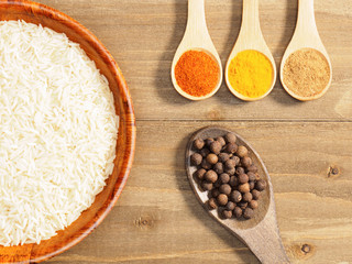Rice, chili pepper, allspice, masala, turmeric on brown wooden background. Indian cuisine, ayurveda, naturopathy, modern apothecary concept