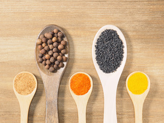 Allspice, black cumin, turmeric, masala, chili pepper on brown wooden background. Indian cuisine, ayurveda, naturopathy, modern apothecary concept