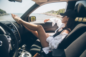 woman sitting in car show sexy legs looking at summer sea beach
