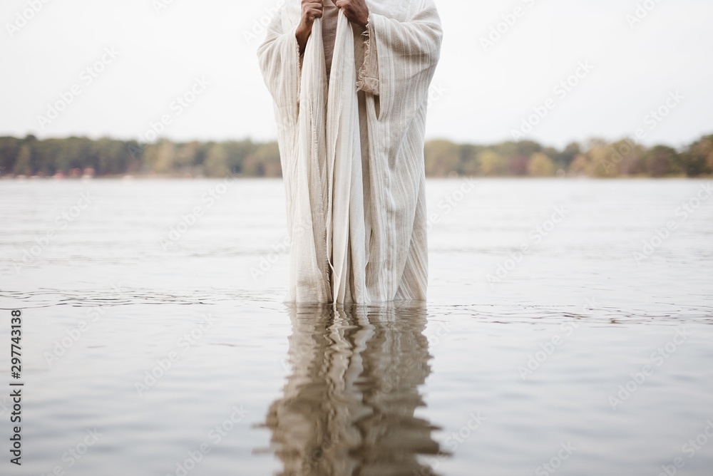 Canvas Prints Person wearing a biblical robe standing in the water with a blurred background