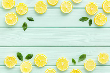 Lemon and leaves pattern on green wooden background top view