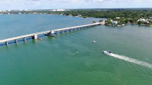 Aerial view of open street bridge crossing ocean with small boat and linking Island Bay and Sarasota, Florida, USA