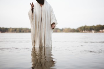 Person wearing a biblical robe standing in the water with a blurred background