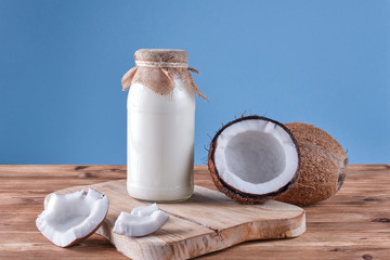 Coconut milk in the bottle on wooden rustic table , blue background . Healthy nutrition concept