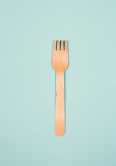One wooden fork on light blue background as a symbol of consumption. Eco and fast food concept.