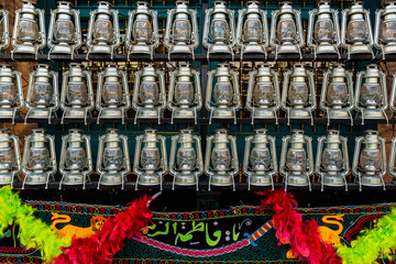 Fototapeta premium kerosene lamps and the name Fatima embroidered on fabric in front of a mosque, as a symbol of religious mourning of Imam Husayn martyrdom, Tehran, Iran