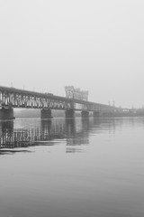 Fototapeta na wymiar Bridge in the morning fog. Iron bridge over the river in mystic fog.