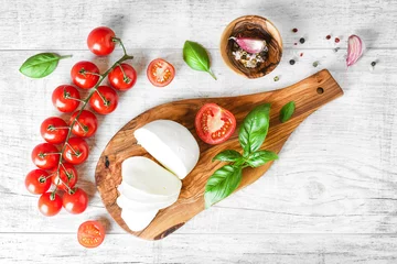 Foto op Plexiglas Fresh finest tomatoes on white rustic board with basil and mozzarella cheese top view. © Milan