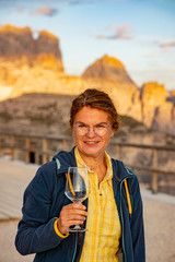 Woman with wineglass enjoys the sunset in the Dolomites