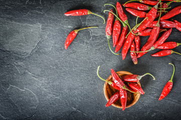 Hot red chili peppers on dark vintage table or black slate background. Dried chilli pepper concept from top view.