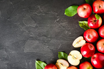 Fresh red bio apples in group on dark stone table from top view. Ripe apple fruits with green...