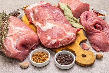 Assorted various pork cuts. Raw meat with spices. Tenderloin, shoulder blade, neck, hind leg steak