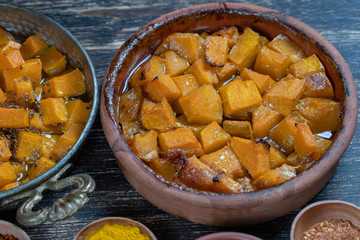 Baked yellow pumpkin with honey, anise, olive oil and spices on a plate on the wooden table. Vegetarian food. Closeup