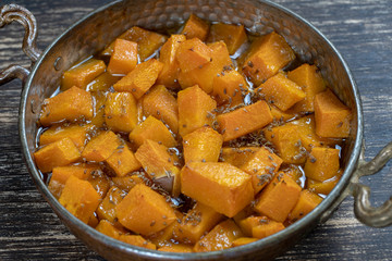 Baked yellow pumpkin with honey, anise, olive oil and spices on a plate on the wooden table. Vegetarian food. Closeup