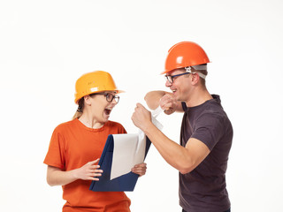 Emotional, young - a man with a woman foreman in yellow helmets with glasses and a folder in his hands on a white background
