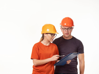 Emotional, young - a man with a woman foreman in yellow helmets with glasses and a folder in his hands on a white background