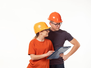Emotional, young - a man with a woman foreman in yellow helmets with glasses and a folder in his hands on a white background