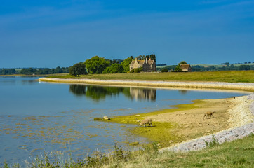 Fototapeta na wymiar Rutland Water a large reservoir in Leicestershire in the summer with ruins in the distance.