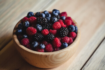 blueberries and raspberries, blackberry in a wooden bowl on old wood background