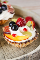 Beautiful cupcakes decorated with fresh fruits: grapes, peach, orange.