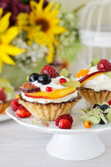 Beautiful cupcakes decorated with fresh fruits: grapes, peach, orange.
