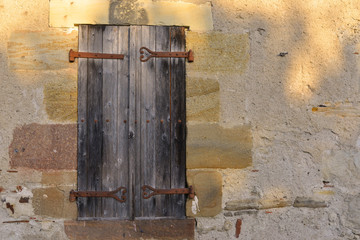 Vieille façade et volets de bois aux éclats de lumière, France