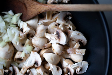 сooking onions and mushrooms on wok pan