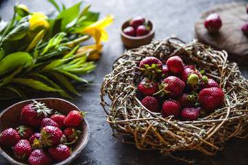 Delicious strawberries with yellow flowers on a dark gray background in a vintage wreath. Healthy