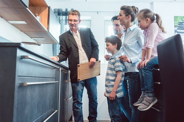 Salesman showing family the features of a new kitchen