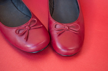 Stylish female flat shoes in dark red color on dark red background. Beauty and fashion concept.