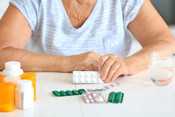 Elderly woman with medicines at home, closeup