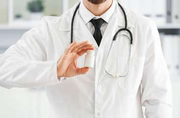 Male doctor with pills in clinic, closeup